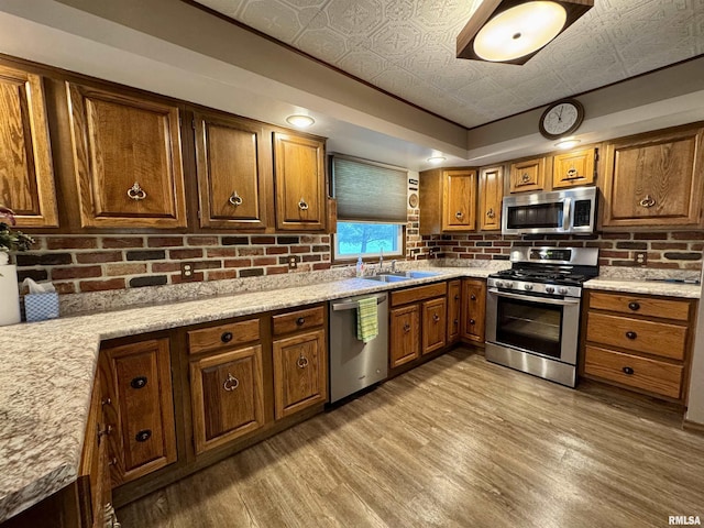 2001 W Jackson St Unit C, Macomb, IL 61455 - kitchen featuring stainless steel appliances, an ornate ceiling, brown cabinetry, light wood finished floors, and decorative backsplash