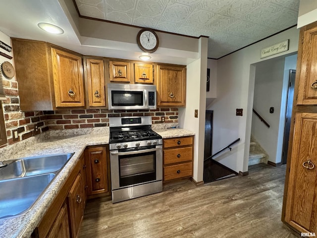 2001 W Jackson St Unit C, Macomb, IL 61455 - kitchen with stainless steel appliances, brown cabinetry, decorative backsplash, dark wood-type flooring, and an ornate ceiling