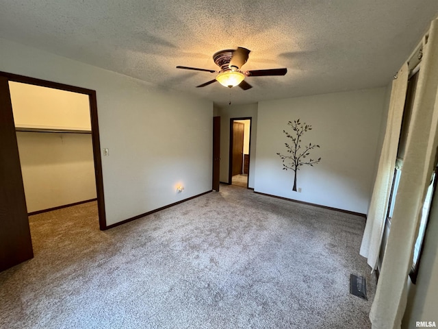 2001 W Jackson St Unit C, Macomb, IL 61455 - unfurnished bedroom with carpet, a textured ceiling, a walk in closet, and a ceiling fan