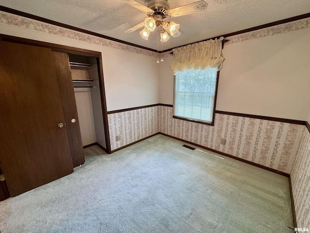 2001 W Jackson St Unit C, Macomb, IL 61455 - unfurnished bedroom featuring wallpapered walls, a textured ceiling, carpet, a closet, and a wainscoted wall