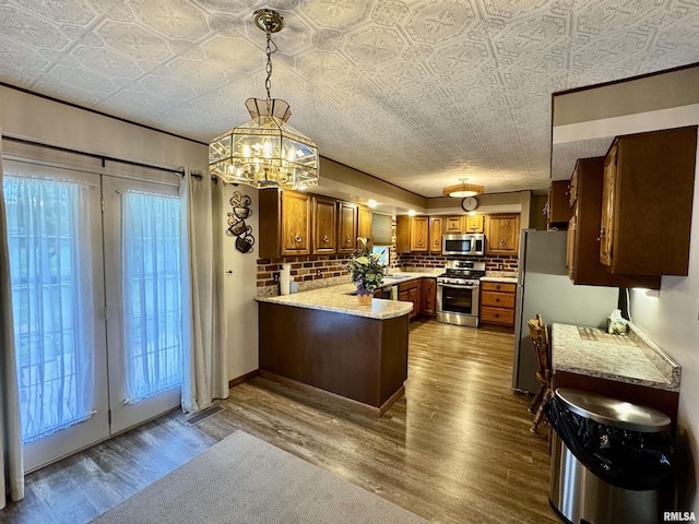 2001 W Jackson St Unit C, Macomb, IL 61455 - kitchen featuring appliances with stainless steel finishes, brown cabinetry, an ornate ceiling, a peninsula, and dark wood finished floors