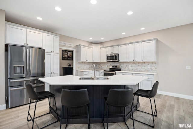 109 E Lee St, Tremont, IL 61568 - kitchen featuring stainless steel appliances, a breakfast bar, an island with sink, decorative backsplash, and light wood-style flooring