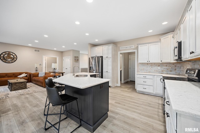 109 E Lee St, Tremont, IL 61568 - kitchen with stainless steel appliances, a breakfast bar, light wood-style flooring, white cabinetry, and recessed lighting