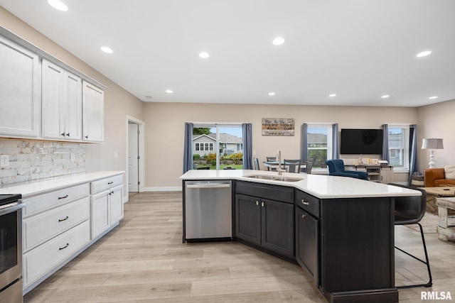 109 E Lee St, Tremont, IL 61568 - kitchen featuring stainless steel appliances, open floor plan, a breakfast bar area, light wood-type flooring, and white cabinetry