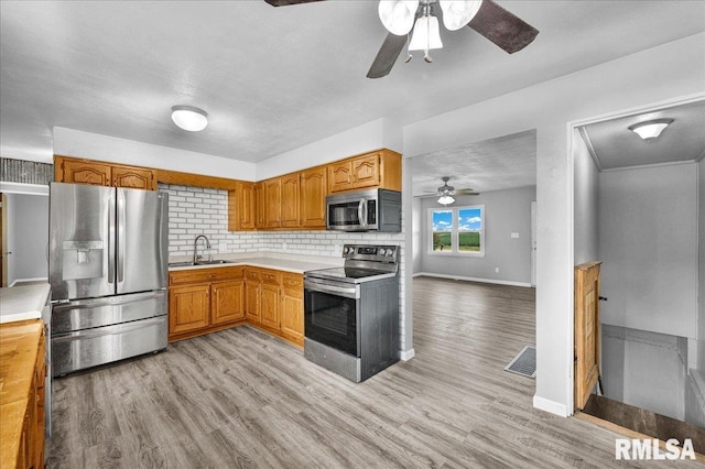 14100 Glasford-Canton Rd, Glasford, IL 61533 - kitchen with appliances with stainless steel finishes, ceiling fan, light countertops, light wood finished floors, and decorative backsplash