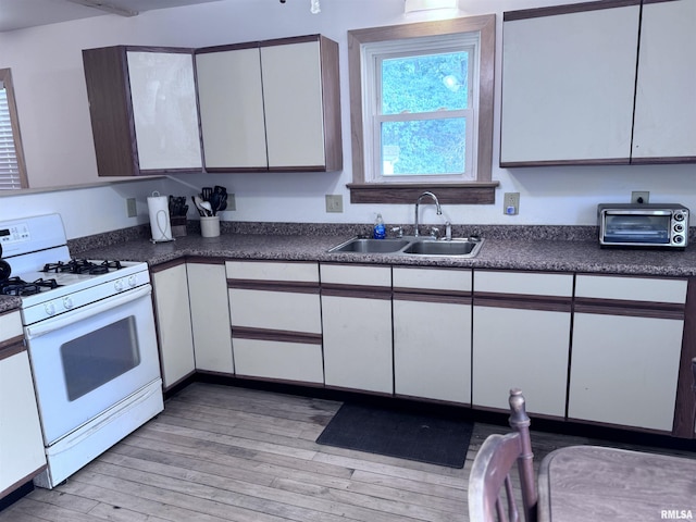 1807 N 5th St, Chillicothe, IL 61523 - kitchen with white gas range oven, light wood-style floors, white cabinets, and dark countertops