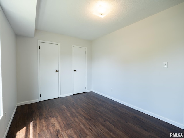 6110 N Idlewhile Dr, Peoria, IL 61614 - unfurnished bedroom with baseboards and dark wood-type flooring