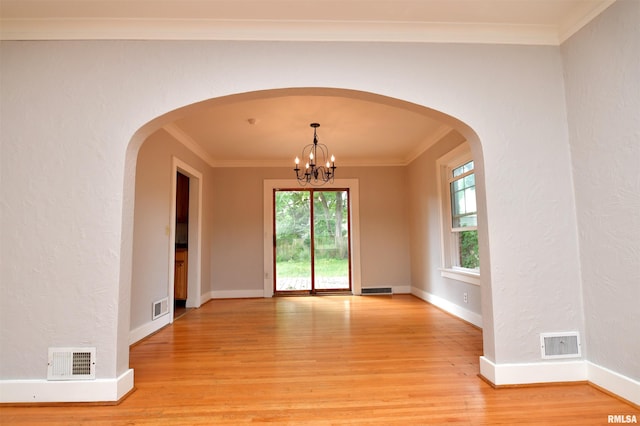 300 E Embert Pl, Peoria, IL 61603 - empty room with light wood finished floors, ornamental molding, a chandelier, and arched walkways