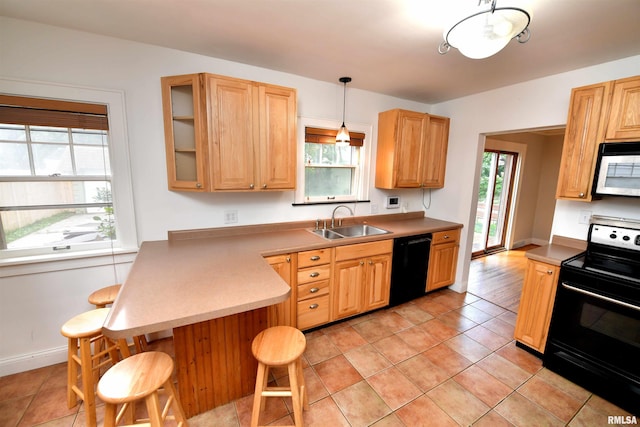 300 E Embert Pl, Peoria, IL 61603 - kitchen with black appliances, a breakfast bar, a peninsula, glass insert cabinets, and light countertops