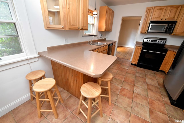 300 E Embert Pl, Peoria, IL 61603 - kitchen featuring black appliances, a kitchen bar, a peninsula, light countertops, and light tile patterned flooring