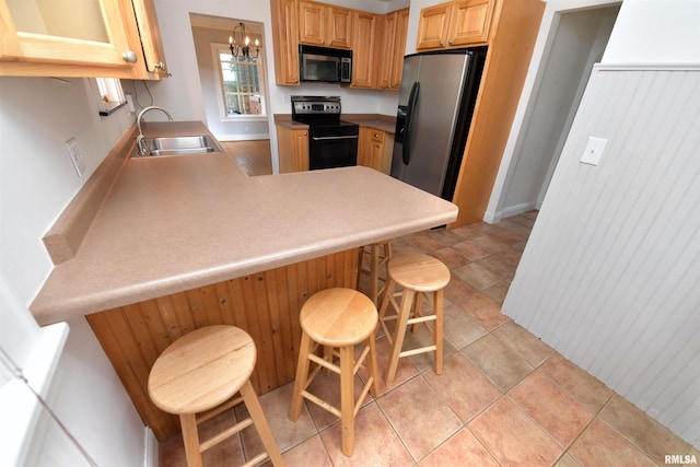300 E Embert Pl, Peoria, IL 61603 - kitchen with stainless steel appliances, a peninsula, a kitchen bar, a chandelier, and light countertops