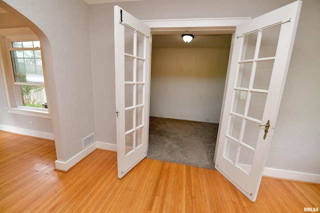 300 E Embert Pl, Peoria, IL 61603 - spare room featuring french doors, arched walkways, and light wood-style flooring
