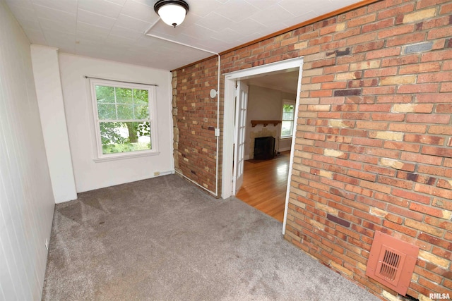 300 E Embert Pl, Peoria, IL 61603 - unfurnished room with carpet, healthy amount of natural light, a fireplace, and brick wall