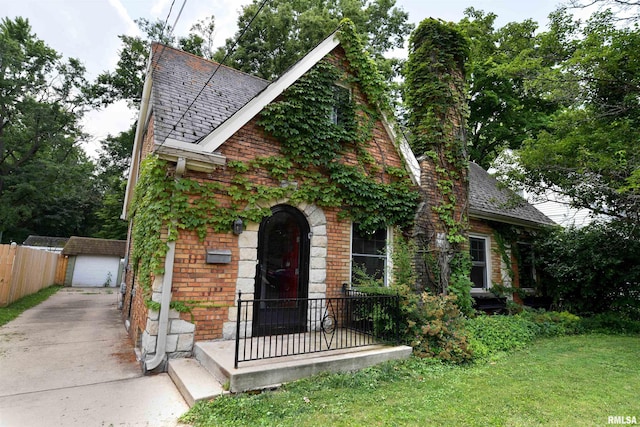 300 E Embert Pl, Peoria, IL 61603 - tudor home with an outbuilding, brick siding, a shingled roof, and a garage