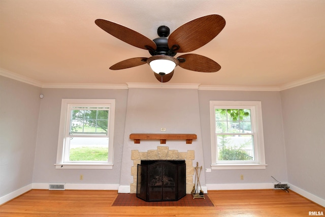 300 E Embert Pl, Peoria, IL 61603 - unfurnished living room featuring healthy amount of natural light, wood finished floors, crown molding, a ceiling fan, and a fireplace with flush hearth