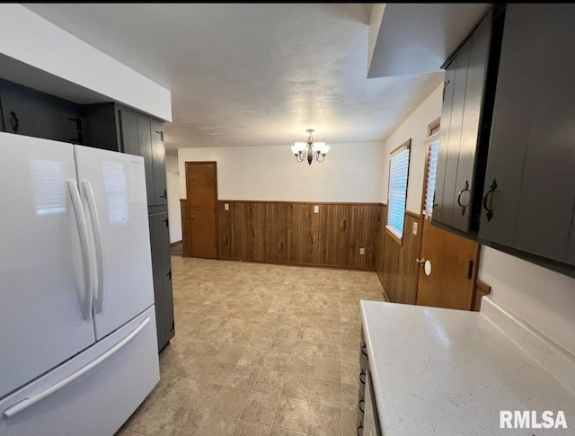 337 N Dr, Morton, IL 61550 - kitchen featuring freestanding refrigerator, wainscoting, wood walls, a chandelier, and light countertops