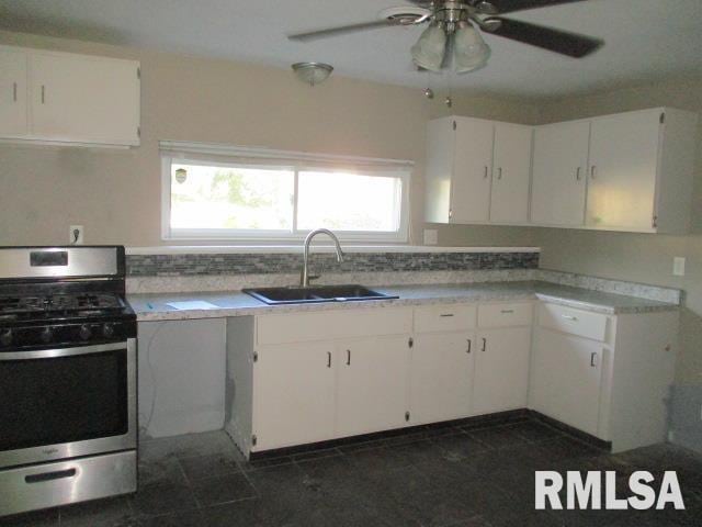 203 Arrow St, Pekin, IL 61554 - kitchen with stainless steel gas range oven, white cabinets, ceiling fan, and light countertops