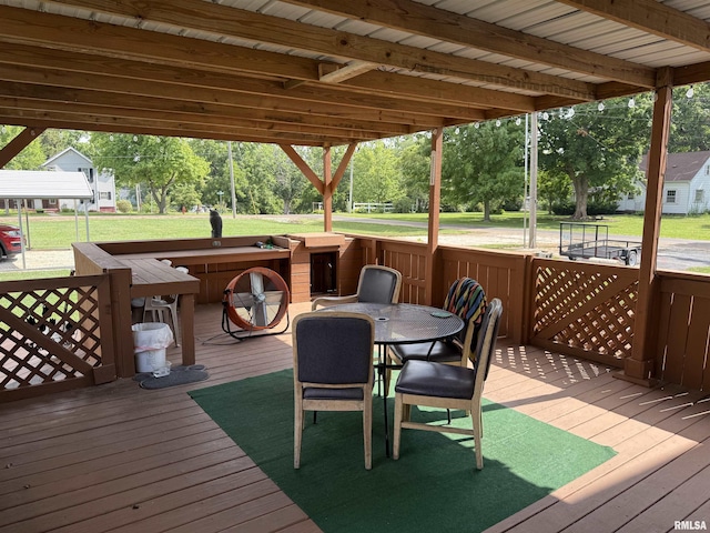 628 E Macarthur Ave, Lewistown, IL 61542 - wooden terrace featuring outdoor dining space, a lawn, and view of wooded area