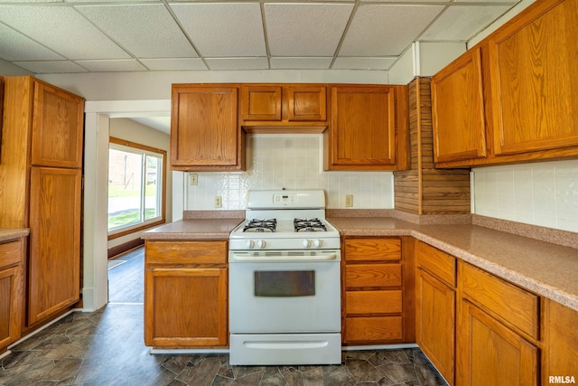 339 Herman St, Pekin, IL 61554 - kitchen with white gas range oven, a drop ceiling, backsplash, stone finish flooring, and brown cabinetry