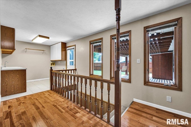 303 W 3rd Ave, Deer Creek, IL 61733 - hall featuring light wood-style floors, a textured ceiling, and an upstairs landing