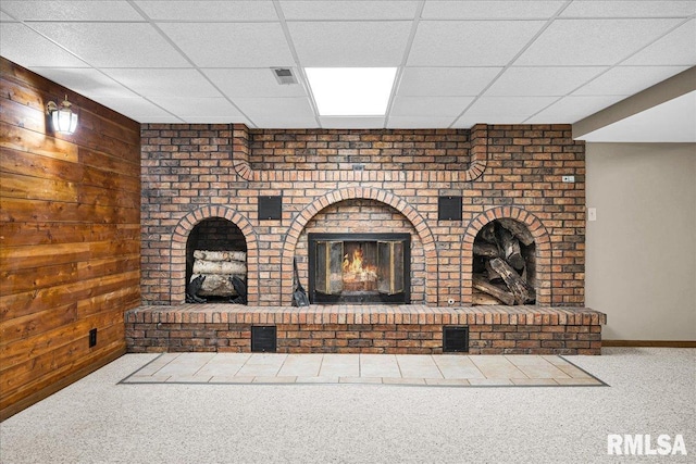 303 W 3rd Ave, Deer Creek, IL 61733 - unfurnished living room featuring a fireplace, carpet flooring, a paneled ceiling, and wooden walls