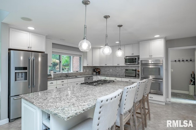 408 W Ravinwoods Rd, Peoria, IL 61615 - kitchen featuring appliances with stainless steel finishes, open shelves, white cabinetry, a kitchen island, and light stone countertops