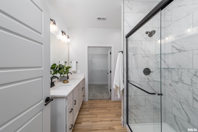361 E Donahue St, Eldridge, IA 52748 - bathroom featuring double vanity, a stall shower, wood finished floors, a walk in closet, and baseboards