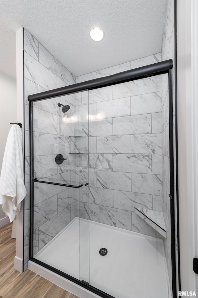 bathroom with walk in shower, hardwood / wood-style floors, and a textured ceiling