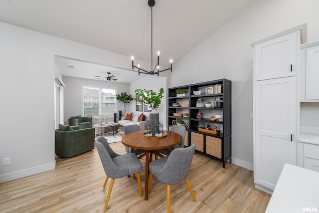 dining room featuring light hardwood / wood-style floors, ceiling fan with notable chandelier, and vaulted ceiling