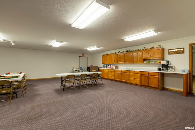 kitchen with dark colored carpet and a textured ceiling