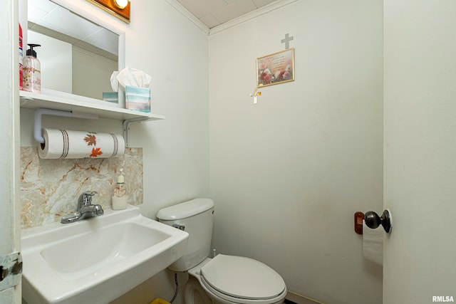 bathroom featuring toilet, ornamental molding, and sink