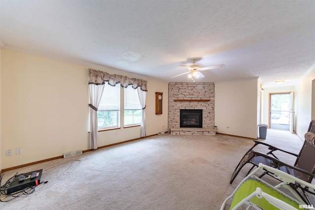 unfurnished living room with ceiling fan, a fireplace, brick wall, light carpet, and a textured ceiling