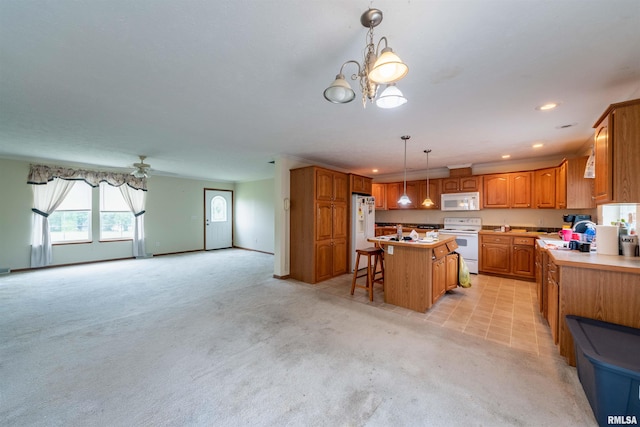 kitchen featuring white appliances, an inviting chandelier, a center island, a breakfast bar area, and light colored carpet