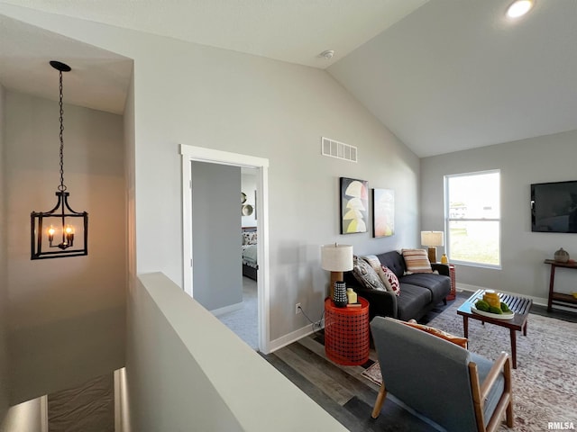 living room featuring a chandelier, dark hardwood / wood-style floors, and vaulted ceiling