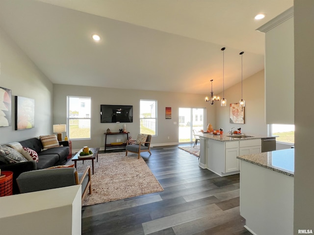 living room featuring a wealth of natural light, dark hardwood / wood-style floors, lofted ceiling, and an inviting chandelier