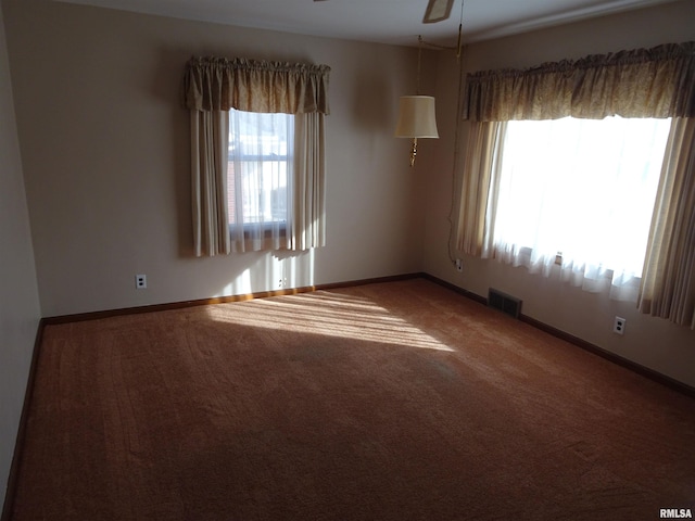 spare room featuring visible vents, baseboards, a ceiling fan, and carpet flooring