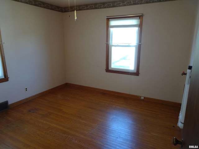 unfurnished room with visible vents, baseboards, and wood finished floors