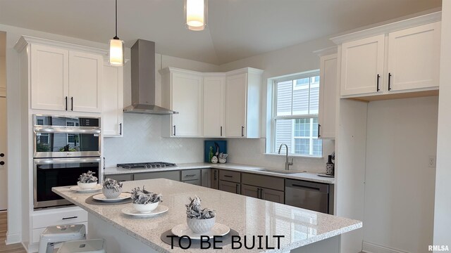 kitchen featuring a breakfast bar area, stainless steel appliances, decorative backsplash, a sink, and wall chimney range hood