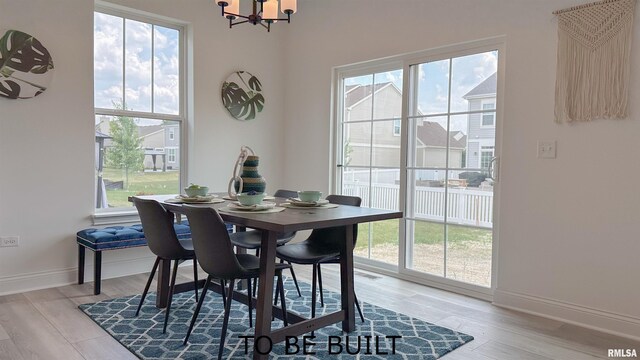 dining area with light wood-style flooring, baseboards, and a notable chandelier