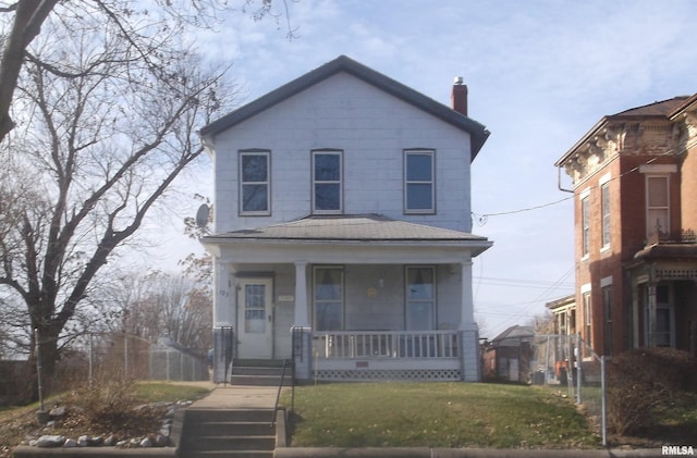 view of front of house featuring a porch, a front yard, and a chimney