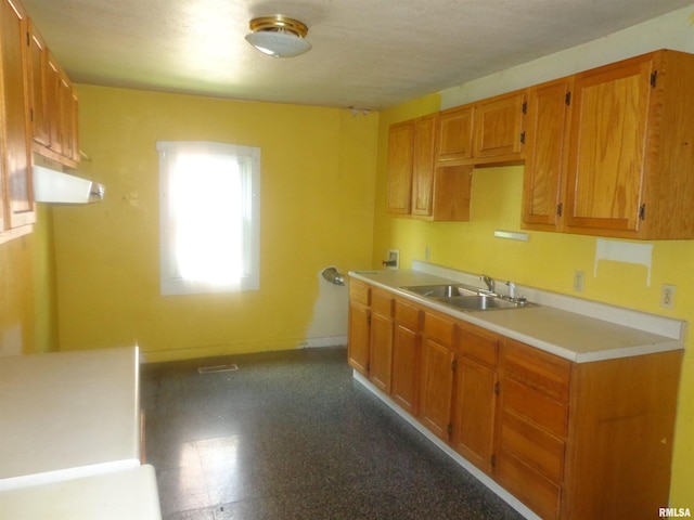 kitchen with brown cabinets, light countertops, baseboards, and a sink