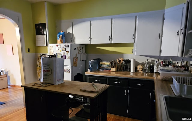 kitchen with white cabinetry, white fridge, and light hardwood / wood-style floors