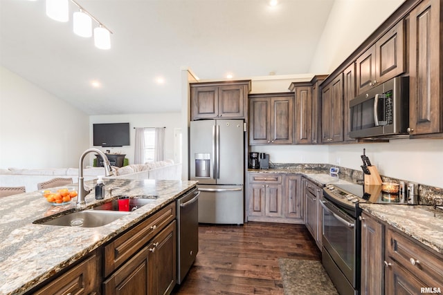 kitchen with sink, light stone counters, dark brown cabinets, stainless steel appliances, and dark wood-type flooring