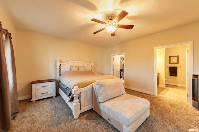 carpeted bedroom featuring ceiling fan, a spacious closet, ensuite bath, and a closet