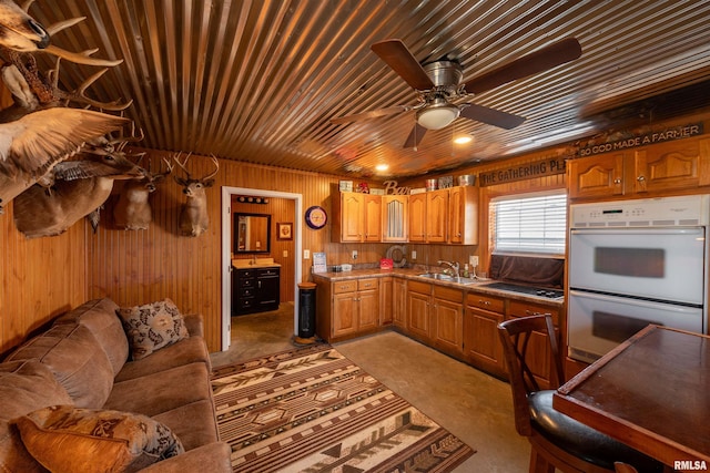 kitchen featuring ceiling fan, sink, double oven, wooden ceiling, and light carpet