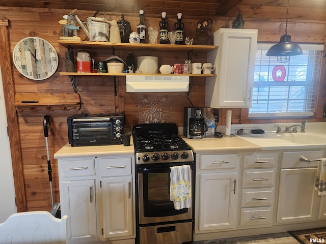 kitchen with stainless steel gas stove, wooden walls, fume extractor, and decorative light fixtures