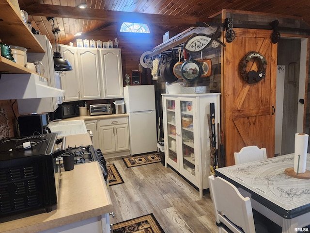 kitchen with wooden walls, lofted ceiling with beams, light wood-type flooring, white refrigerator, and wood ceiling