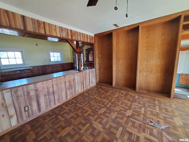 spare room with dark parquet flooring, ceiling fan, and wooden walls