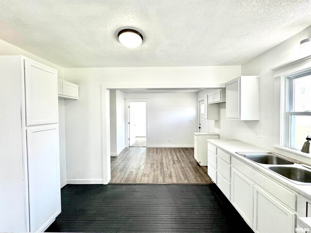 kitchen with dark hardwood / wood-style flooring, white cabinets, a textured ceiling, and sink