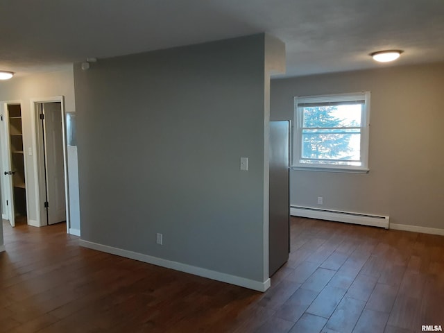 unfurnished room featuring baseboard heating and dark wood-type flooring